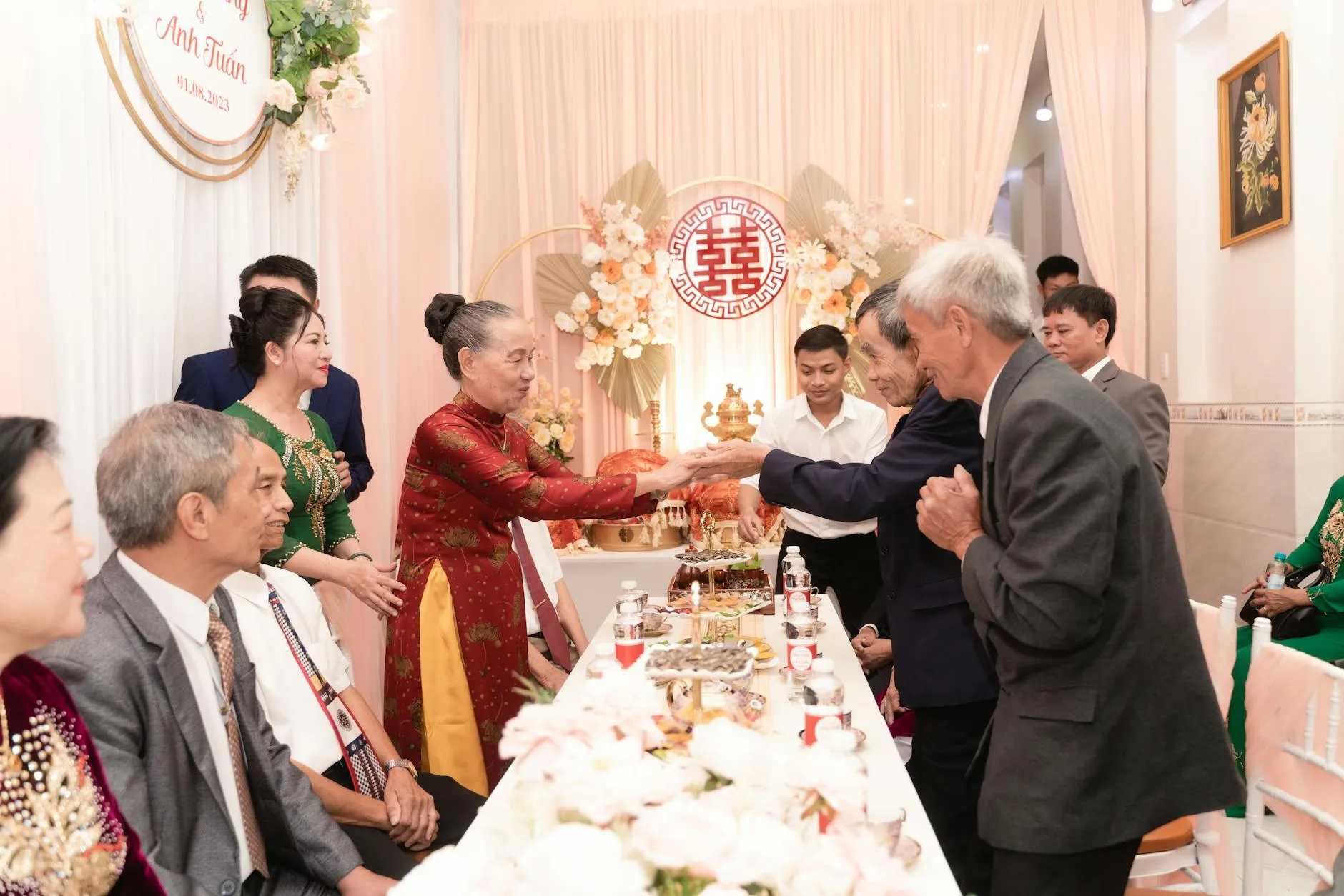 Đại diện nhà trai đang phát biểu trong lễ hỏi truyền thống Việt Nam, bên cạnh là lễ vật trầu cau và gia đình.